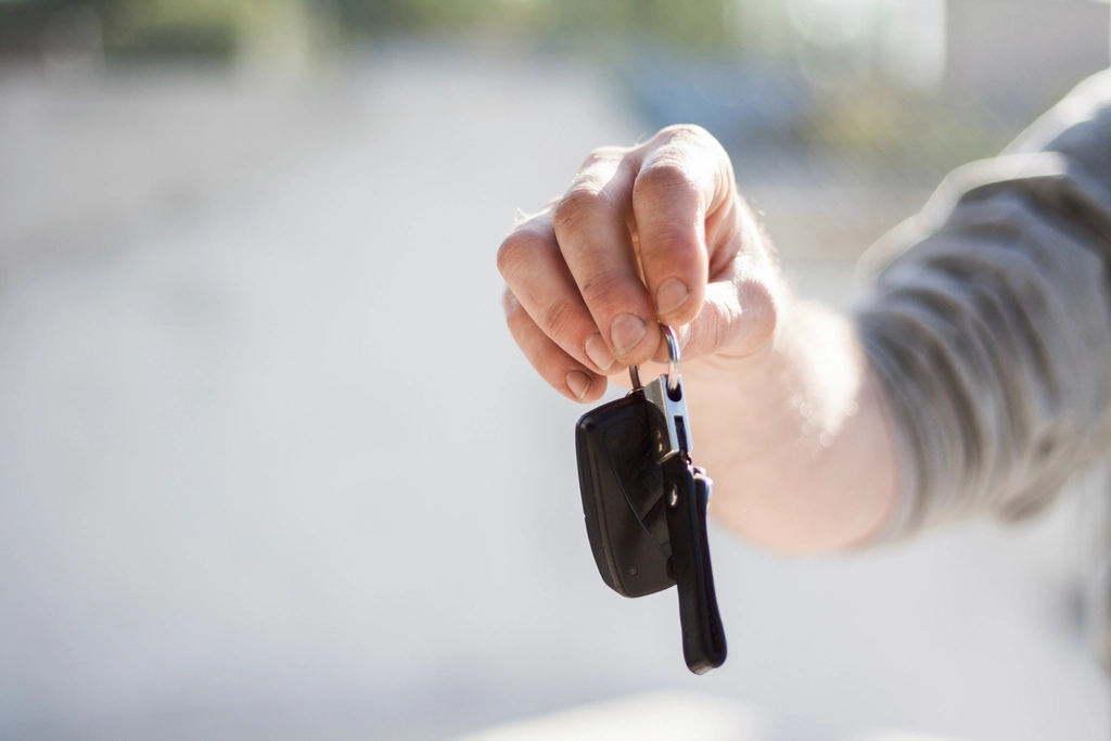 Hand holding out a car key, ready to hand it to the buyer after a private car sale