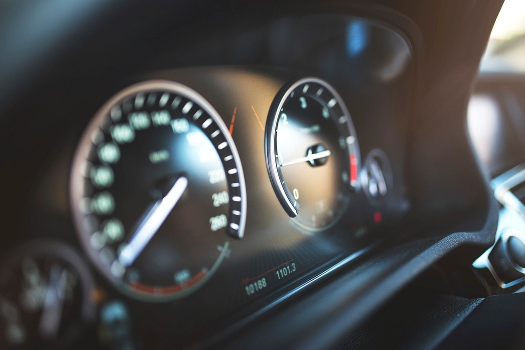 Close-up of a lit car instrument cluster, where mileage and warning lights are checked during an appraisal